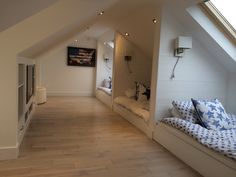 an attic bedroom with white walls and wood flooring on the side, along with built - in windows