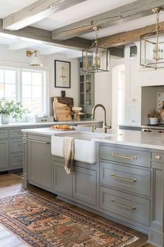 a kitchen with gray cabinets and white counter tops, an area rug on the floor