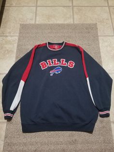 an old buffalo bills sweatshirt laying on the floor next to a tile flooring area