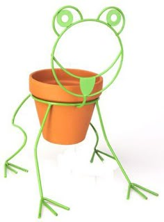 a frog shaped planter sitting on top of a white floor next to a potted plant