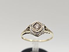 an antique style diamond ring with filigrees on the sides, set in yellow gold