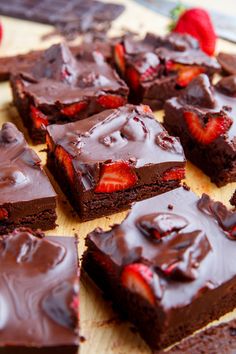 chocolate brownies with strawberries are on a cutting board