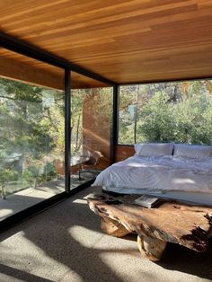 a bed sitting under a window next to a wooden bench in a room with glass walls