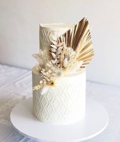 there is a white cake with gold feathers on it