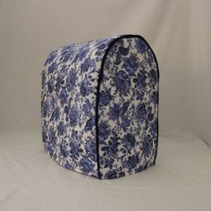 a blue and white flowered bag sitting on top of a white sheet covered floor