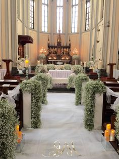 an aisle decorated with greenery and candles in front of a church pew filled with white linens