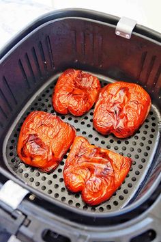 four pieces of cooked tomatoes are in the air fryer and placed on top of each other