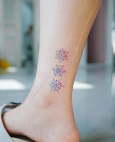 a woman's foot with a small flower tattoo on her left side calfocks