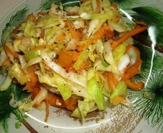 a salad with carrots, onions and other vegetables on a green leafy plate