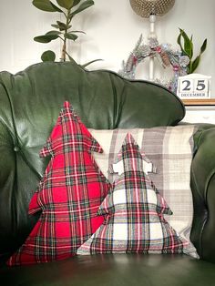 a christmas tree pillow on a green leather couch in front of a potted plant