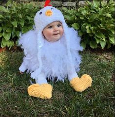 a baby wearing a chicken costume sitting in the grass