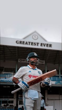 a man holding a cricket bat in front of a stadium with the words greatest ever written on it