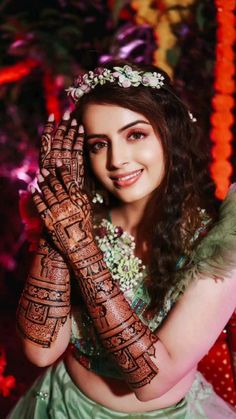 a beautiful woman with henna on her hands and arms, posing for the camera