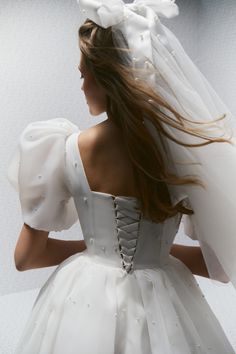 a woman in a white wedding dress with a veil on her head and long hair