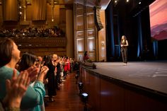 a woman standing on top of a stage in front of a crowd