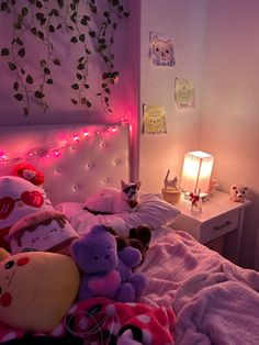 there are many stuffed animals laying on the bed in this room with pink lights and decorations