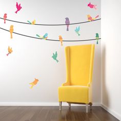 a yellow chair sitting on top of a hard wood floor next to a white wall