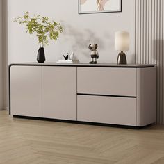 a white sideboard with two vases and a plant on it in a room