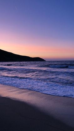 the sun is setting over the ocean with waves coming in