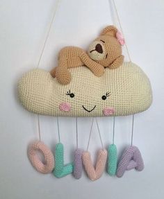 a stuffed teddy bear sitting on top of a cloud with the word love hanging from it