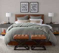 a large bed with two wooden foot stools in front of it and pictures on the wall