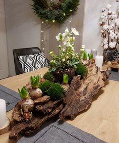 a wooden table topped with lots of flowers and greenery next to a white candle