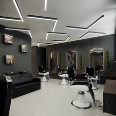 a salon with black and white chairs and mirrors on the walls, lights above them