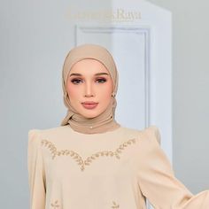 a woman wearing a hijab standing in front of a door with her hands on her hips