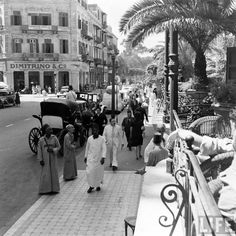 an old black and white photo of people walking down the street