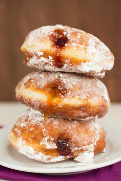 three donuts stacked on top of each other with powdered sugar and fruit toppings