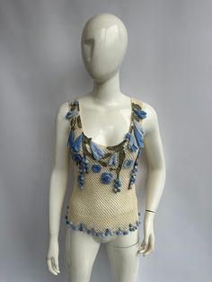 a white mannequin with blue flowers on it's chest and arms, standing in front of a gray background