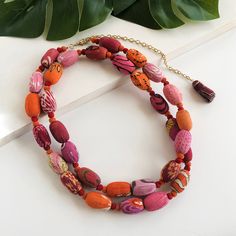 Elongated pink, red and orange Kantha textile beads are interspersed with tiny pom-poms to form a bold strand of color and texture. This long necklace can be worn doubled or tripled for different styling options. Each piece is made from recycled Kantha textiles, so colors and patterns are all one-of-a-kind and will vary. Measures 36" long with a 6" extender. Sustainably handmade by women artisans in India. Long Bead Necklace, Textile Necklace, Kantha Fabric, Headband Jewelry, Handmade Fair, Bead Necklaces, Fabric Necklace, Long Beaded Necklace, Beautiful Gift Wrapping