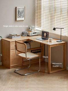 a computer desk with a laptop on top of it next to a window covered in blinds