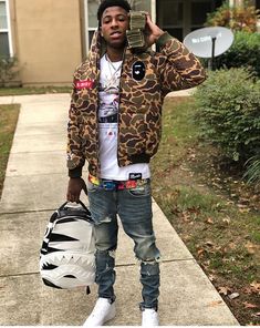 a young man holding a skateboard and wearing a jacket with an animal print on it