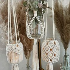 three macrame hangings with flowers and plants in them on a shelf next to a mirror