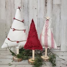 three white and red christmas trees sitting on top of a wooden table next to each other