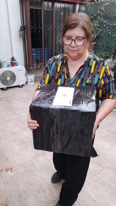 an older woman holding a black box in her hands