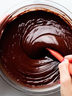 two hands are spreading chocolate in a bowl