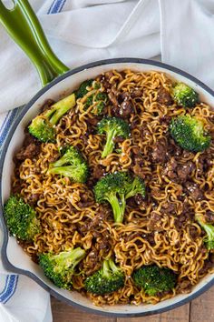 a skillet filled with beef and broccoli on top of a wooden table