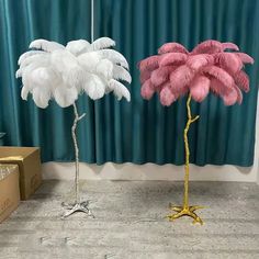 two pink and white ostrich feathers are standing next to each other in front of a blue curtain