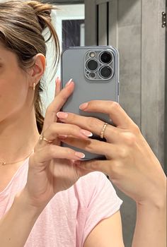 a woman taking a selfie with her cell phone in front of her face and wearing a pink shirt