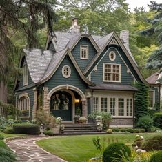 a green house with lots of windows and bushes around it's front door, surrounded by greenery