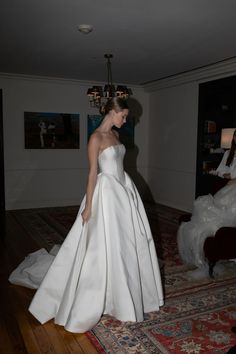 a woman in a white dress is standing on a rug