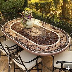 an outdoor table with chairs and a vase on it