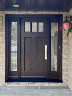 a brown front door with two sidelights on the outside and brick wall behind it