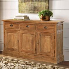 a wooden sideboard with two drawers and a potted plant on top of it