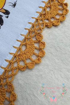 the crochet is on top of the white cloth with yellow trimmings