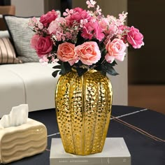 a vase filled with pink flowers sitting on top of a table next to a tissue dispenser