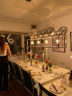 a woman standing in front of a dining room table set with plates and silverware