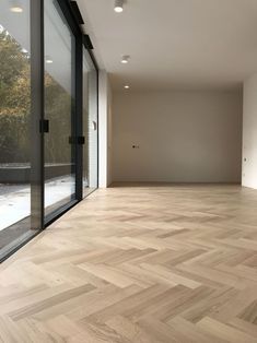 an empty room with wooden floors and large windows